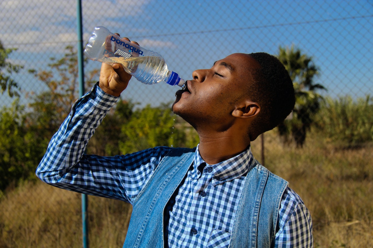 man drinking water from plastic bottle